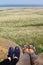 Feet of a travelling couple, green field and blue sky on background