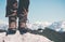 Feet trekking boots on rocky cliff with mountains landscape