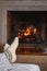 Feet of unrecognizable woman or man in warm white knitted socks and plaid in front of the fireplace. Cozy relaxed magical