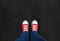 Feet wearing red shoes on black background