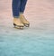 Feet with white skates and legs with the lower part of blue jeans on white ice with blue and red gleam