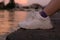 Feet in white sneakers on the blurred river and city background