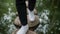 Feet in white sneakers walking on stones path above pond