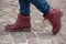 Feet of woman with red winter boots on cobblestone in the street