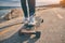 Feet of woman in sneakers on a longboard at the evening