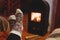 Feet in wool socks warming near fireplace in rustic cabin house. Cozy winter