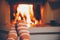 Feet in wool striped socks by the fireplace. Relaxing at Christmas fireplace on holiday evening