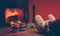 Feet in woollen socks by the Christmas fireplace. Woman relaxes