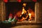 Feet in woollen socks by the fireplace. Woman relaxes by warm