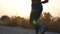 Feet of young active girl jogging on country road with sunrise at background. Female legs running outdoor. Sporty woman