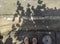 feet of a young man wearing white sandals on the pavement by the roadside.