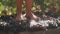 Feet of young woman squeezing grapes in wooden barrel