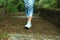 Feet of young woman walking surrounding with fresh green nature background in the forest. Human body part conceptual with copy