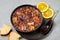 Feijoada in black bowl gray concrete table top. Brazilian and portuguese cuisines traditional beans meat stew