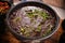 FEIJOADA served in a clay bowl on a rustic wooden table. Brazilian food.