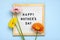 Felt board with text Happy Mother's day, colorful gerberas bouquet on blue backround greeting holiday card Flat lay