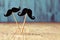 Felt mustaches in sticks on a wooden surface