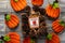 Felt orange pumpkins arranged in a circle on a wooden background, with pine cones and Fresh Cider plaque sign. Top down, flat lay