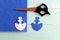Felt piece cut into the shape of an anchor. Scissors, paper template, pins on wooden background. Sewing lesson for kids