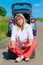 Female 50 years sitting on a spare wheel near the car