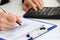 Female accountant hand holding pen counting on calculator