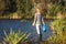 Female activist standing at lake and cleaning water from plastic waste