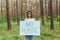 female activist standing in the woods with no plastic poster, volunteer struggling with forest pollution