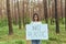 female activist standing in the woods with no plastic poster, volunteer struggling with forest pollution
