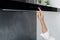 Female adjusting cooker hood while cooking in kitchen