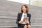 Female administrator sitting on stairs with tablet and working.