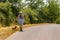 Female adult hiker walking with her dog on left side of a country road