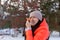 Female adult putting carrot to face as nose on house backyard full of snow in evening having walk with trees and iron