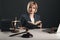 Female advocate with juridical books at her workplace. Gavel and libra on the desk.