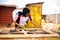 Female African professional carpenter smiling as she takes a measurement of wood