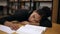 A female afro american student in black sweater, tired and fell asleep on a table with books and notes in the modern