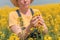 Female agronomist checking up on development of rapeseed crops in field, woman working on plantation