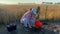 Female agronomist taking soil sample with garden tool bucket at dawn