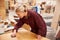 Female Apprentice Finishing Wood In Carpentry Workshop