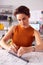 Female Architect At Desk In Office Measuring Plan Or Blueprint With Ruler