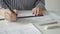 Female architect draws with ruler and pencil, sitting at table in office.