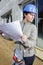 female architect looking at plans outside property