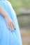 Female arm with ring and manicure on blue dress background.
