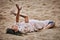Female art dance performance on sandy beach, woman dancer lying on her back on sand and performing