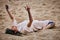 Female art dance performance on sandy beach, woman dancer lying on her back on sand and performing