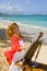 A female artist painting on the beach