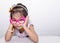 Female asian child girl posing wacky sad lonely pose while wearing some accessories like crown, necklace, pink eye glasses and