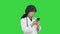 Female asian doctor wearing a white coat and stethoscope looking at x ray on a Green Screen, Chroma Key