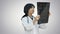 Female asian doctor wearing a white coat and stethoscope looking at x ray on white background