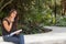 Female asian student sitting outside thinks while writing in not