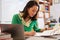 Female Asian teacher at her desk marking studentsï¿½ work